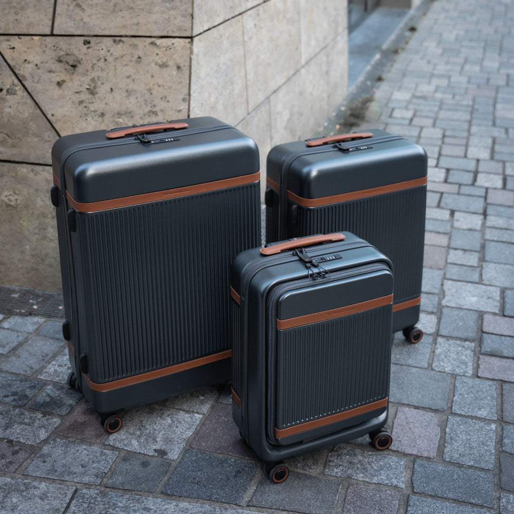 Three suitcases of different sizes on a stone pavement.