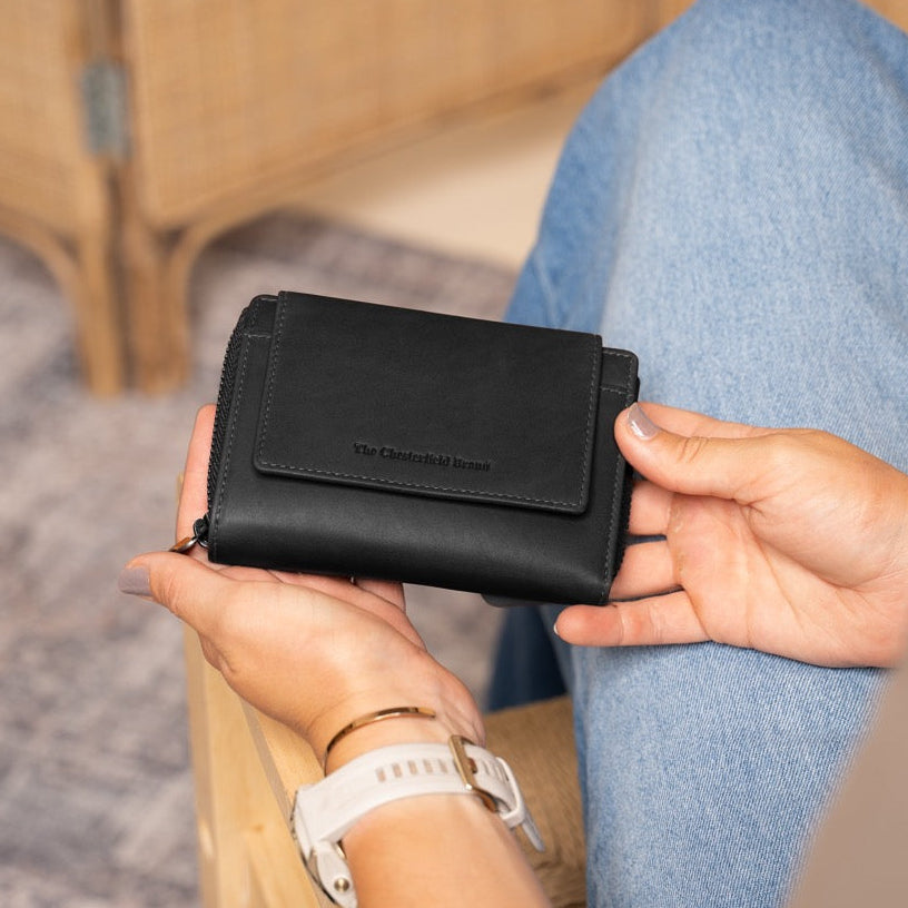 Person holding a black wallet with a blurred background
