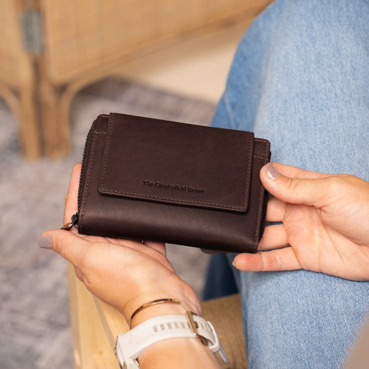 Person holding a brown leather wallet with a blurred background