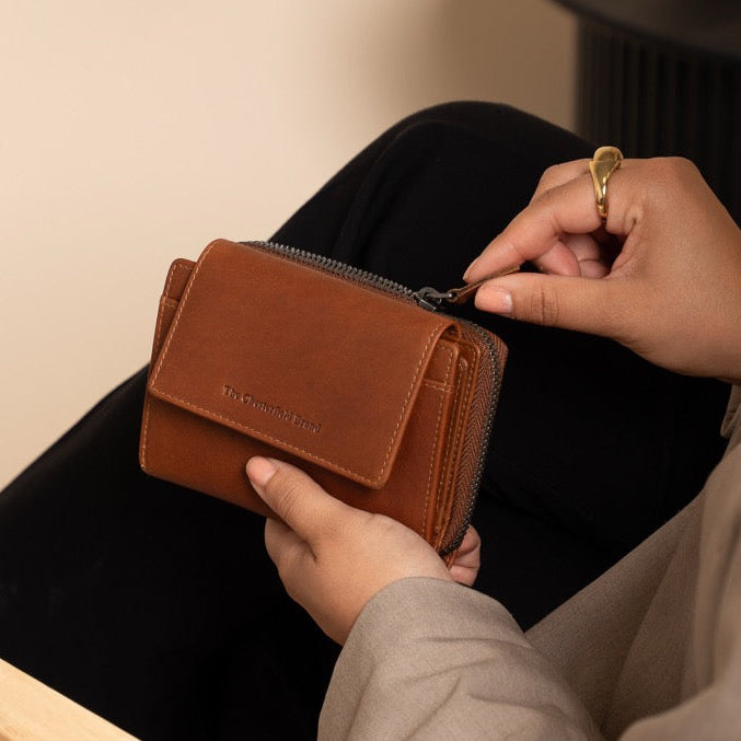 Person sitting on a chair holding a cognac wallet with a neutral background