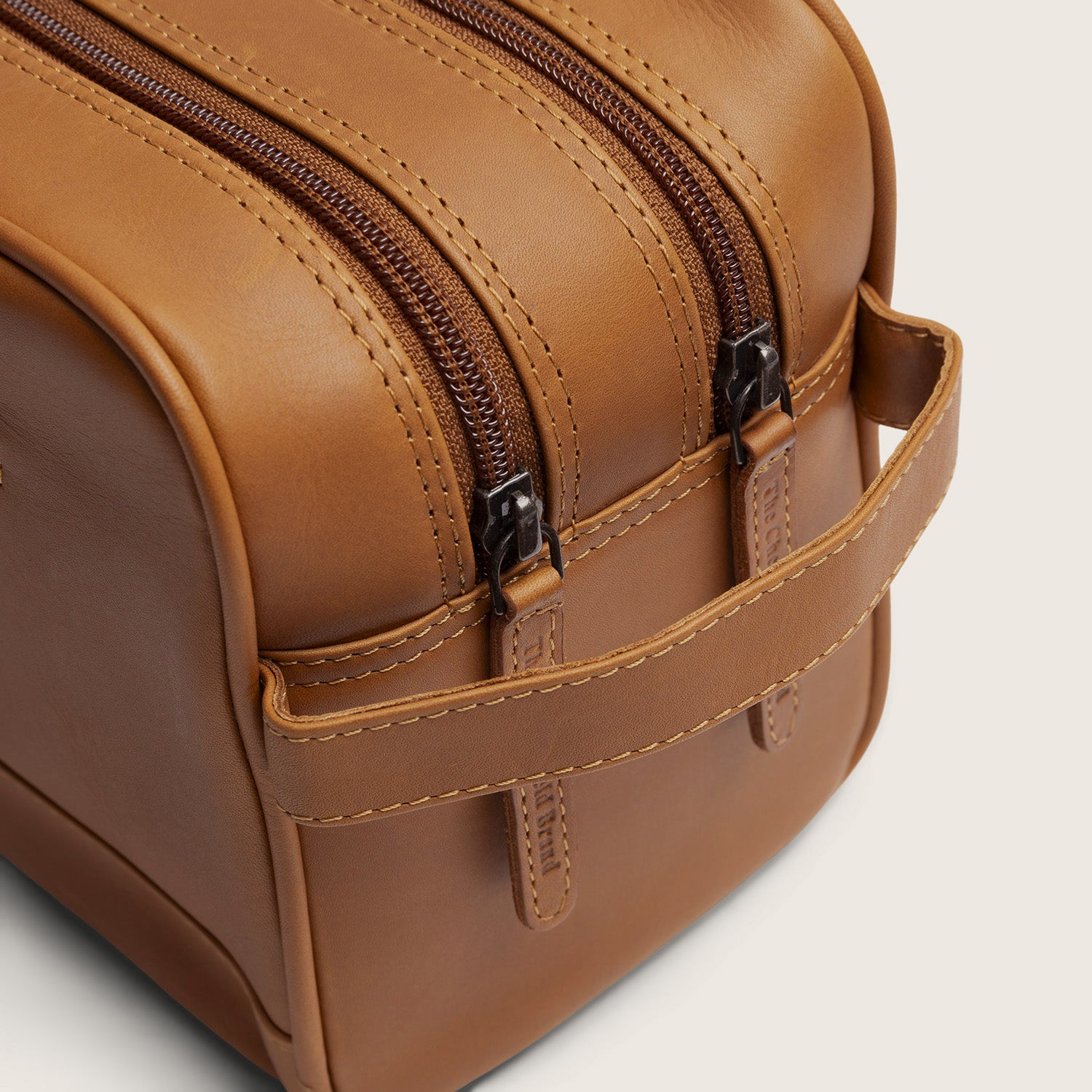 Leren Toilettas Cognac Stefan, close-up van de twee ritsen en het handvat