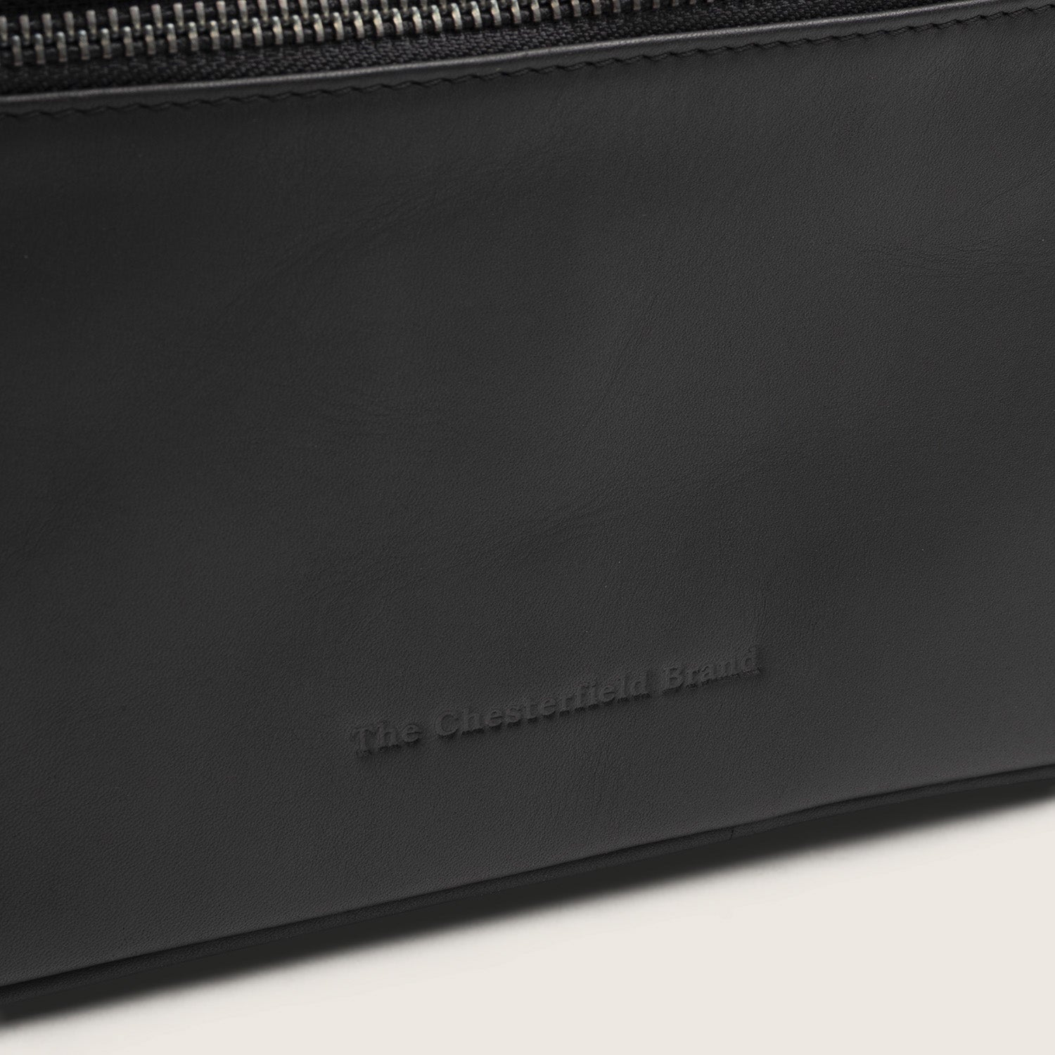 Trousse de Toilette en Cuir Noir Limone, gros plan sur le logo embossé 'The Chesterfield Brand'