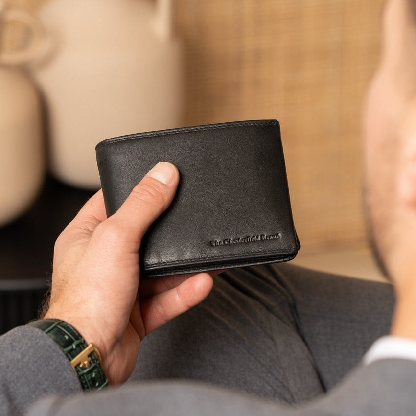 Classic black leather men's wallet with a blurred background.