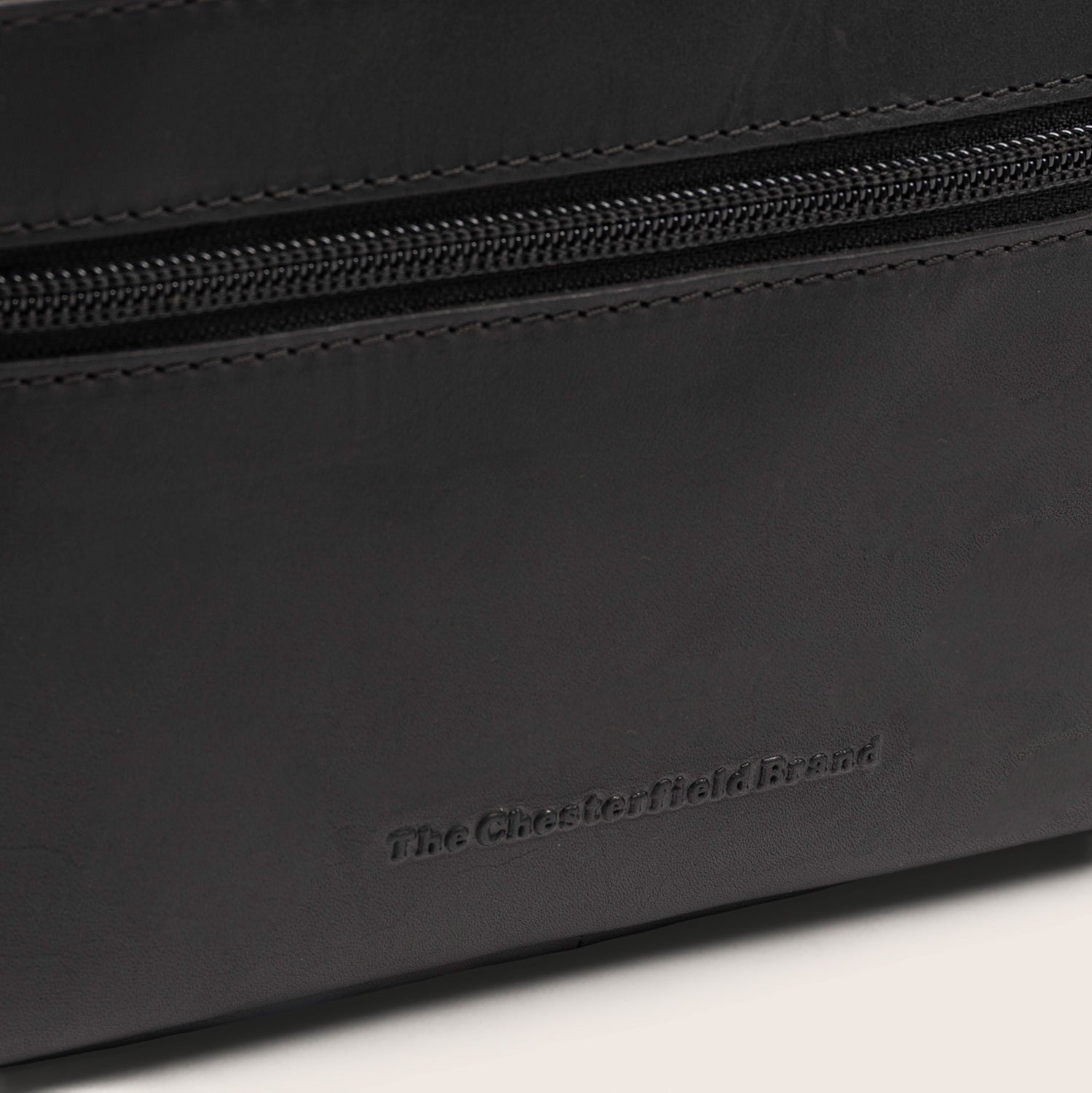 Leren Toilettas Zwart Elmia, close-up van het ingeperste logo 'The Chesterfield Brand'