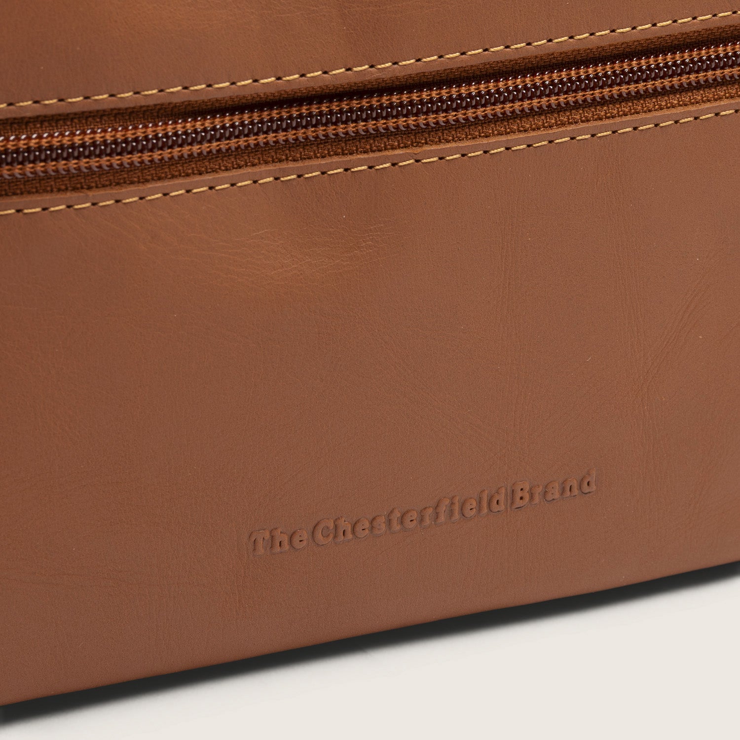 Trousse de Toilette en Cuir Cognac Elmia, gros plan sur le logo embossé 'The Chesterfield Brand'