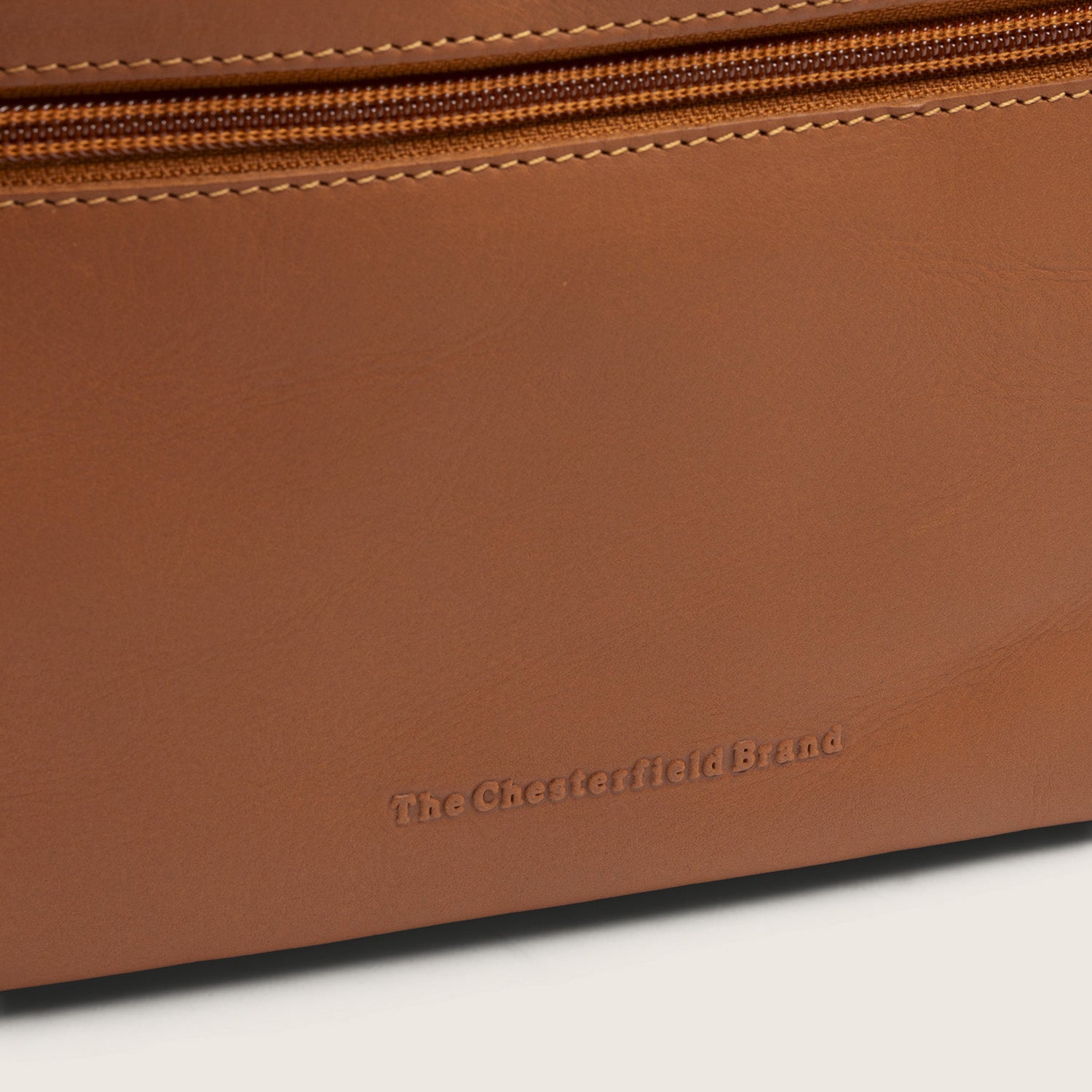 Trousse de Toilette en Cuir Cognac Trevia, gros plan sur le logo embossé