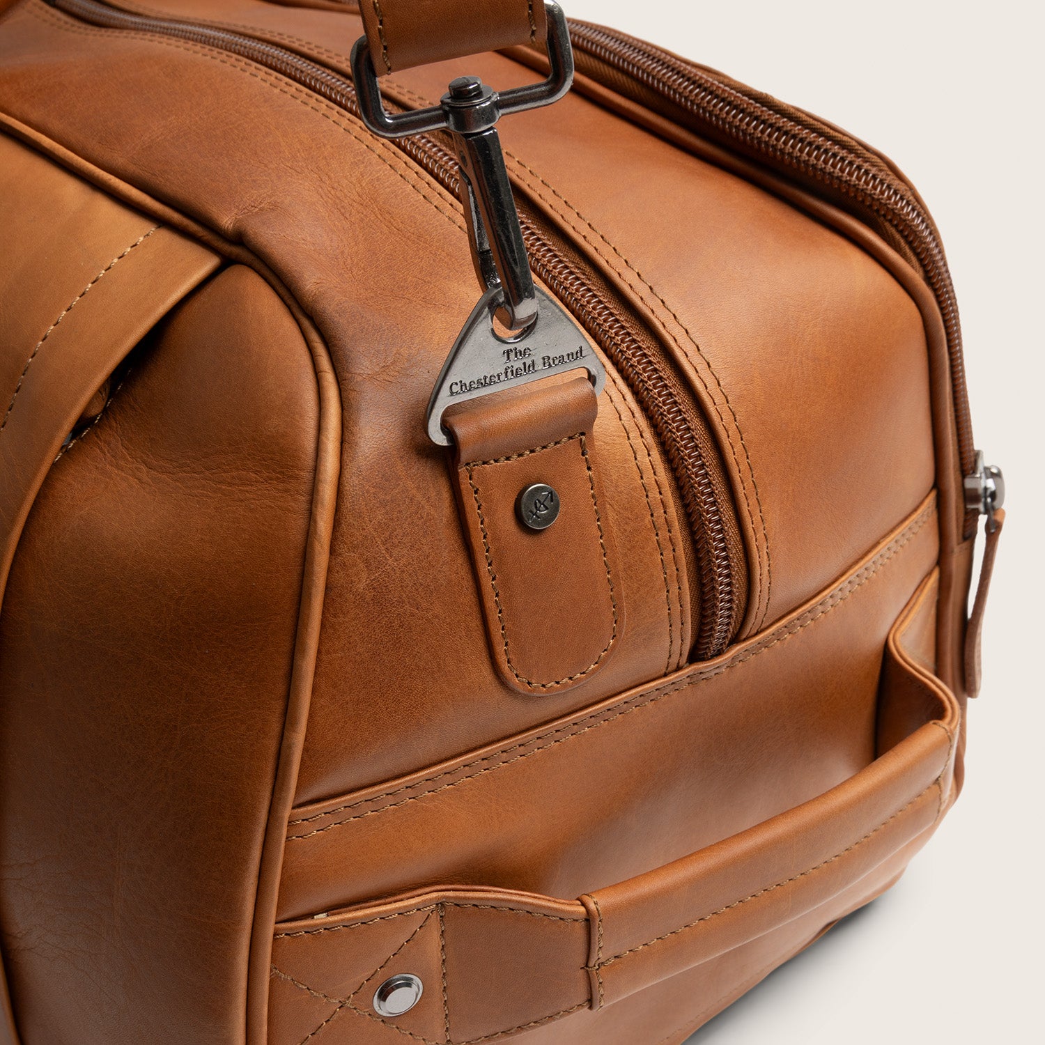 Leren Trolley Weekendtas Cognac Jayven, close-up van de karabijnhaak en metalen ring met gravure 'The Chesterfield Brand'