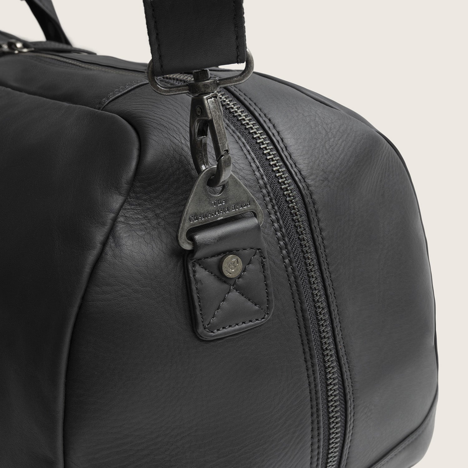 Sac Week-end en Cuir Noir Melbourne, gros plan sur l'attache de la bandoulière, gravée 'The Chesterfield Brand'