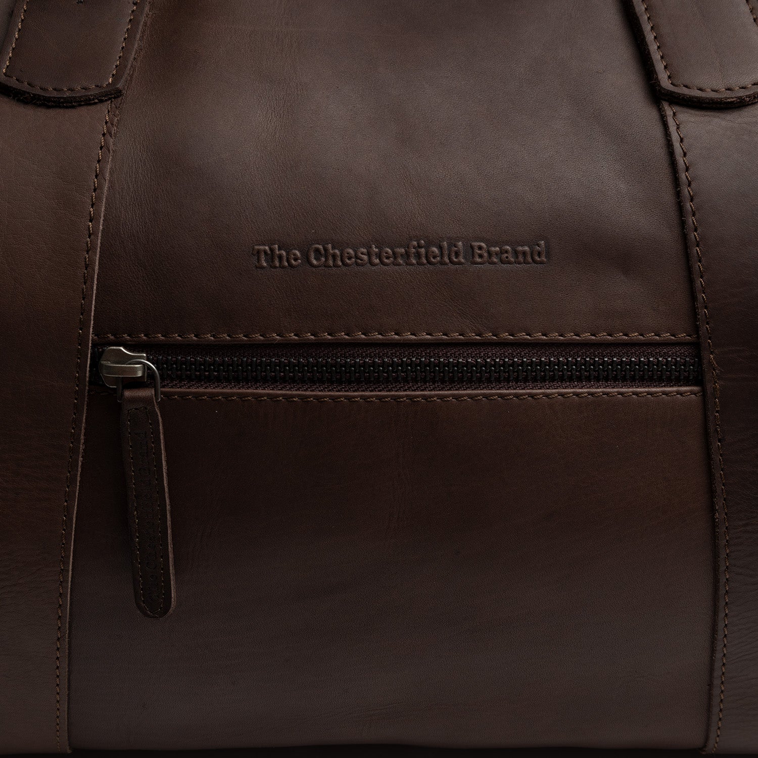 Leather Weekender Bag Brown Portsmouth II, close-up of the embossed logo above the front zip pocket