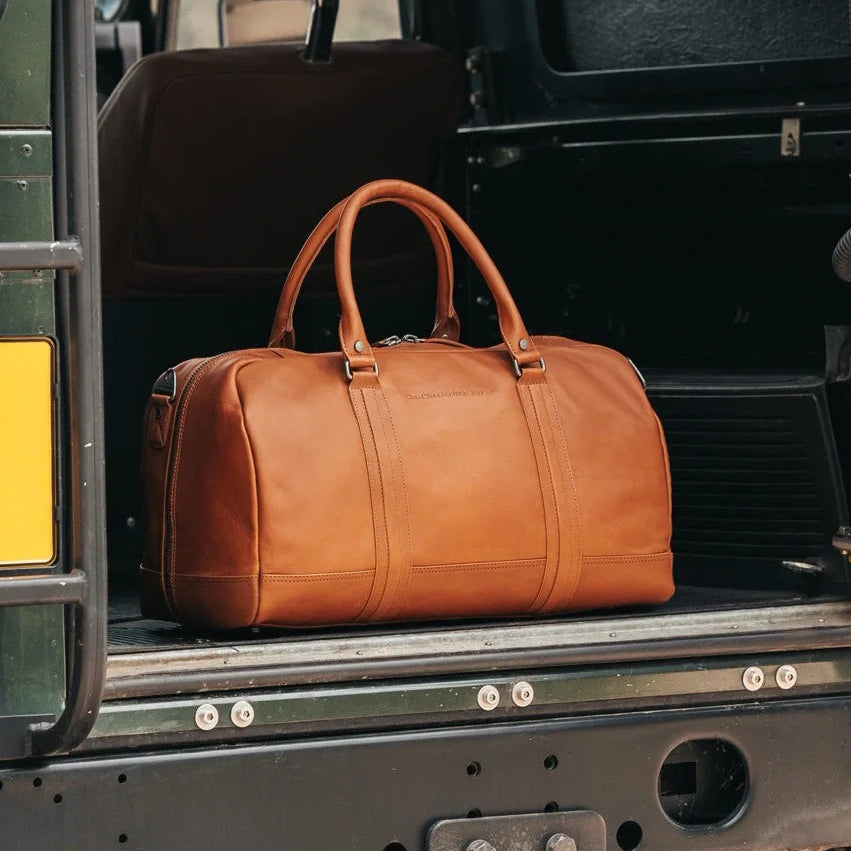 Cognac leather duffel bag on the back of a black vehicle.