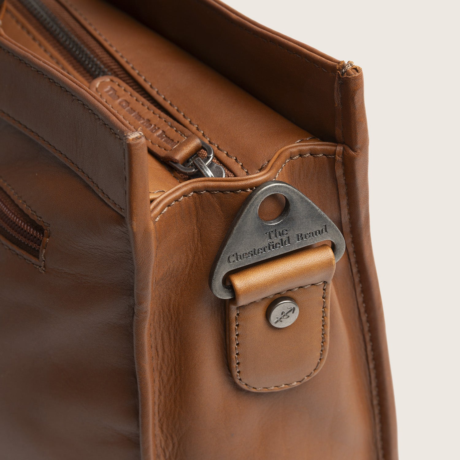 Leder Shopper Cognac Manly, Nahaufnahme des Metallbeschlags für den Gurt mit 'The Chesterfield Brand'