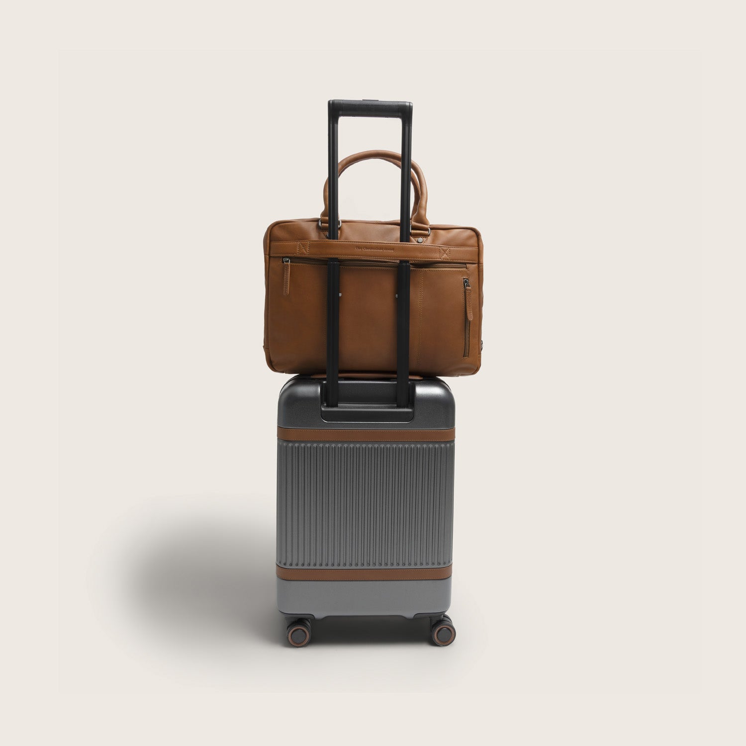 Sacoche Ordinateur en Cuir Cognac Boston, vue de dos, fixée sur une valise avec la sangle trolley