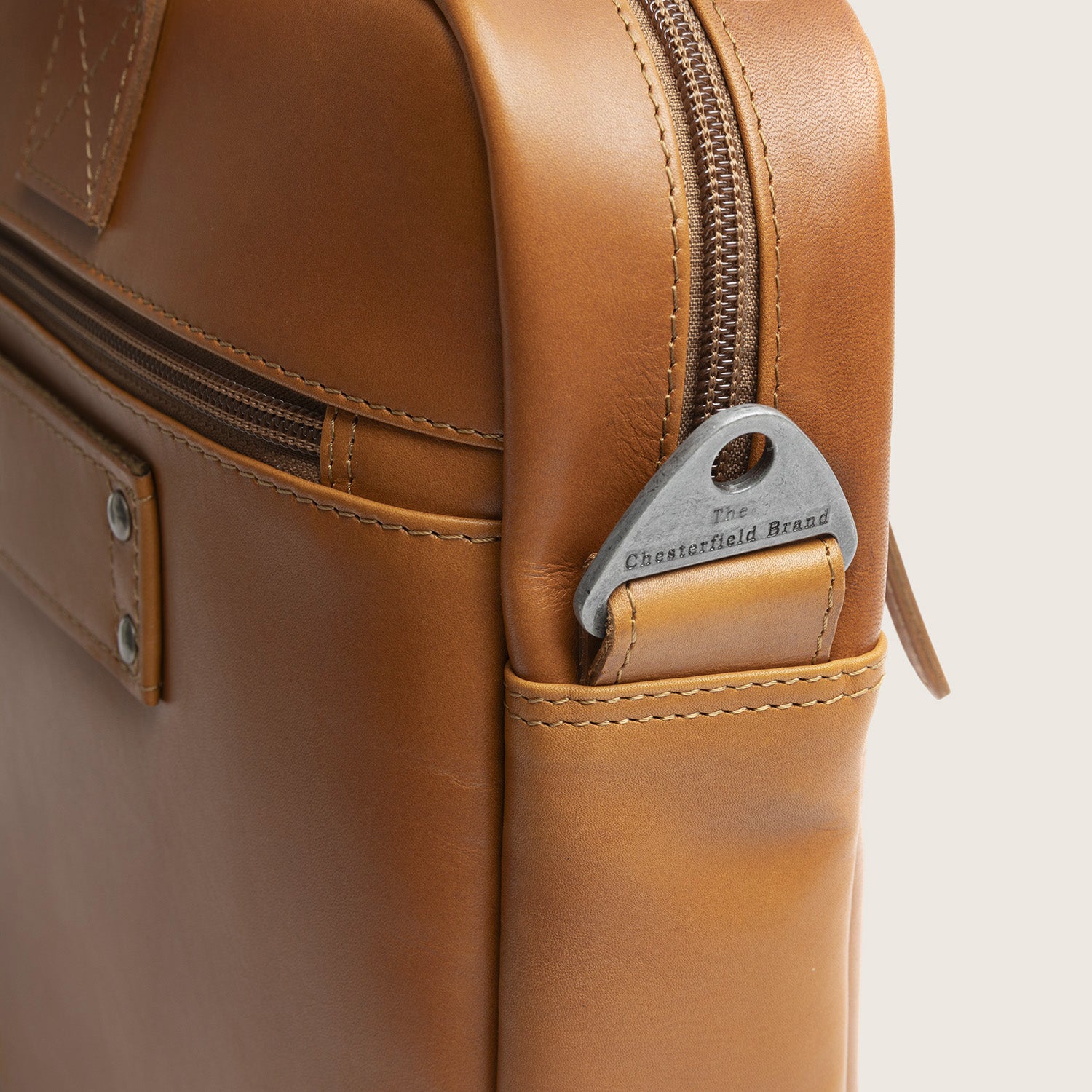 Leren Laptoptas Cognac Calvi, close-up van de bevestiging van de schouderband met gravure 'The Chesterfield Brand'