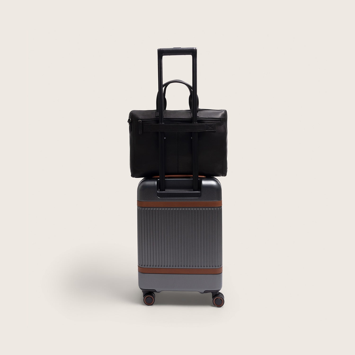 Sacoche Ordinateur en Cuir Noir Levanto, glissée sur la poignée d'une valise à roulettes