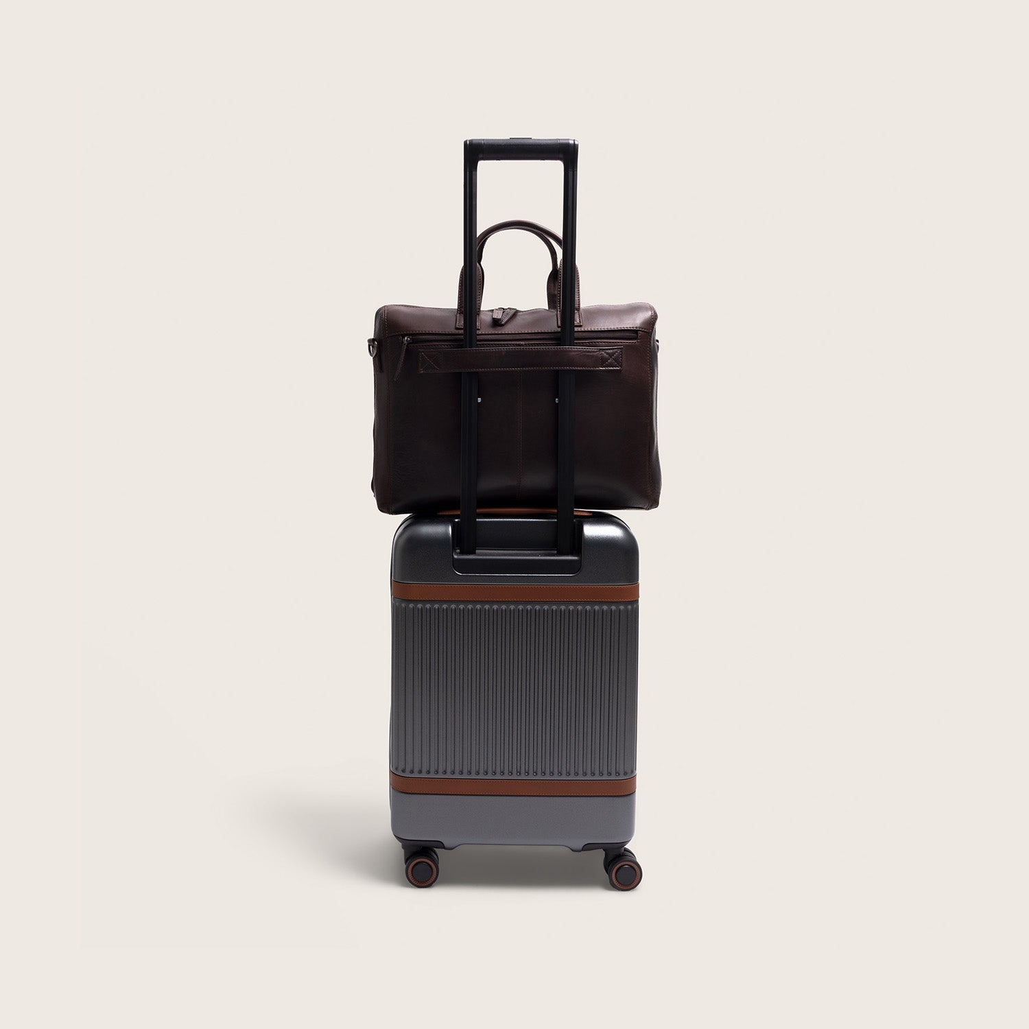 Sacoche Ordinateur en Cuir Marron Levanto, glissée sur la poignée d'une valise à roulettes
