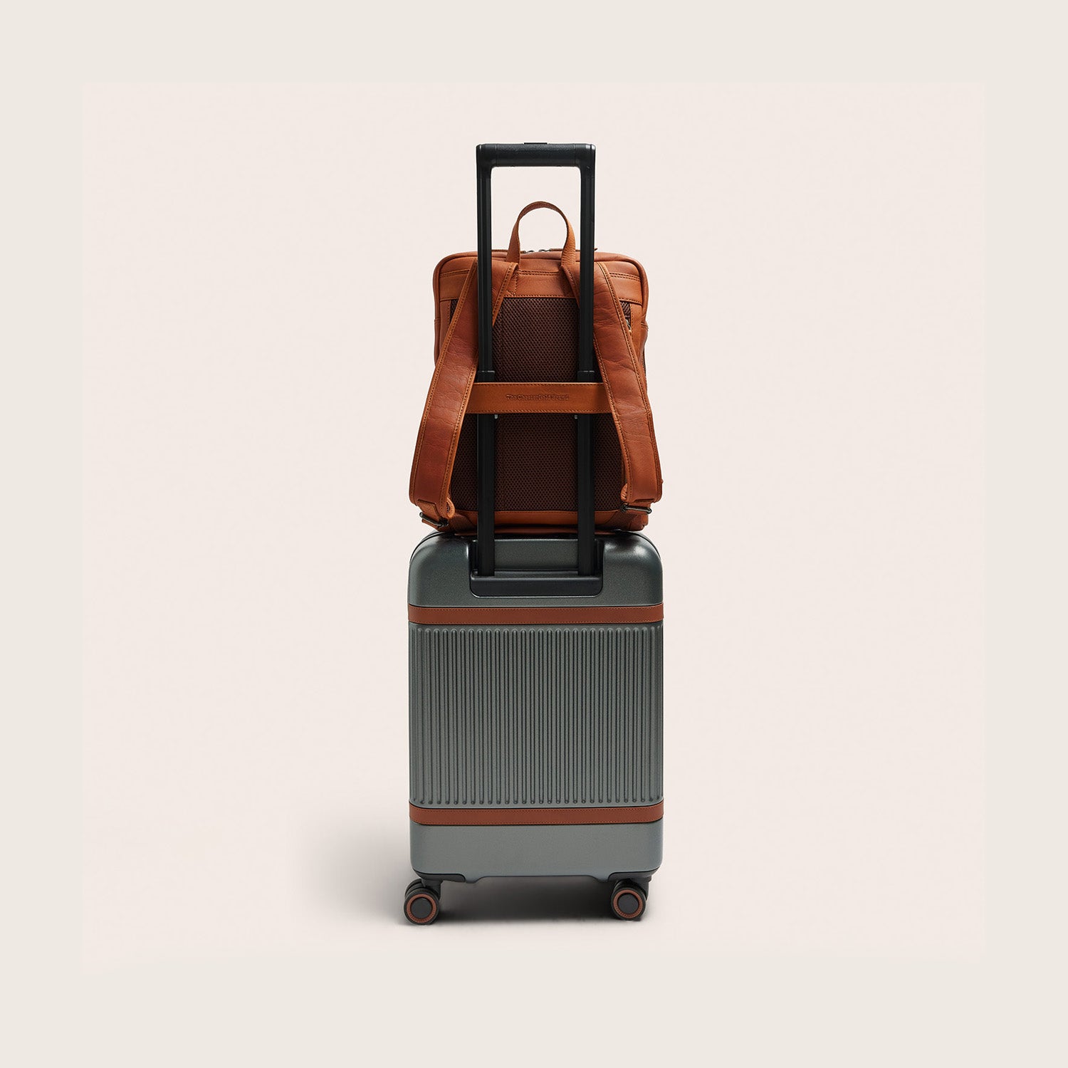Leather Laptop Backpack Cognac Jasper, back view, on a suitcase handle via the trolley strap
