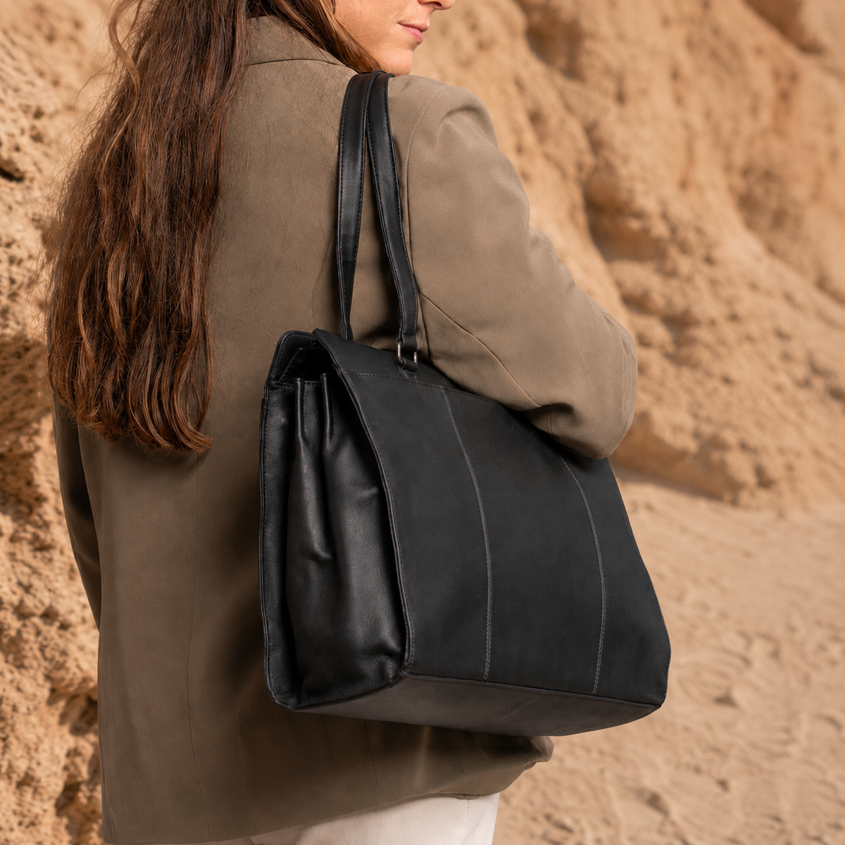 Person wearing a black shoulder bag against a desert background