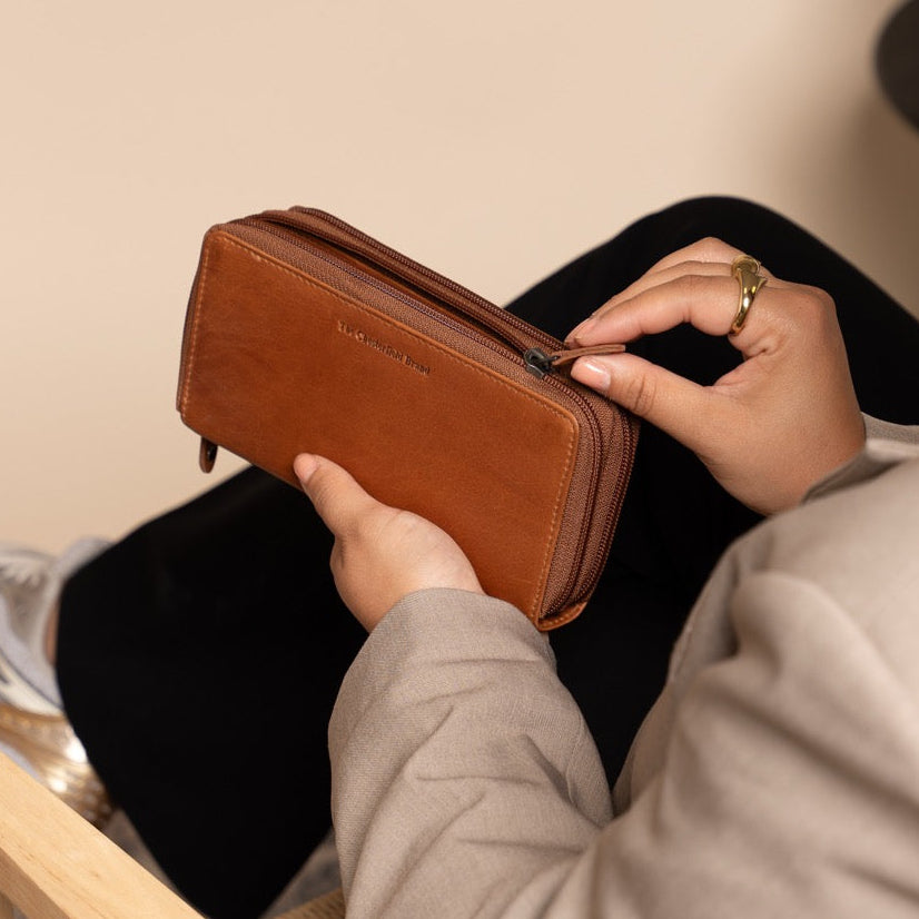 Person holding a cognac leather wallet in a casual setting