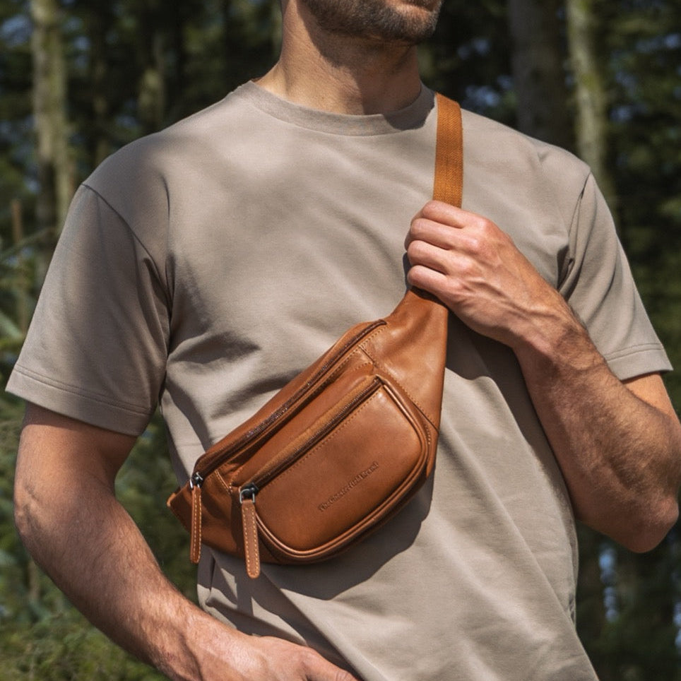 Man wearing a cognac leather waist bag in a forest setting