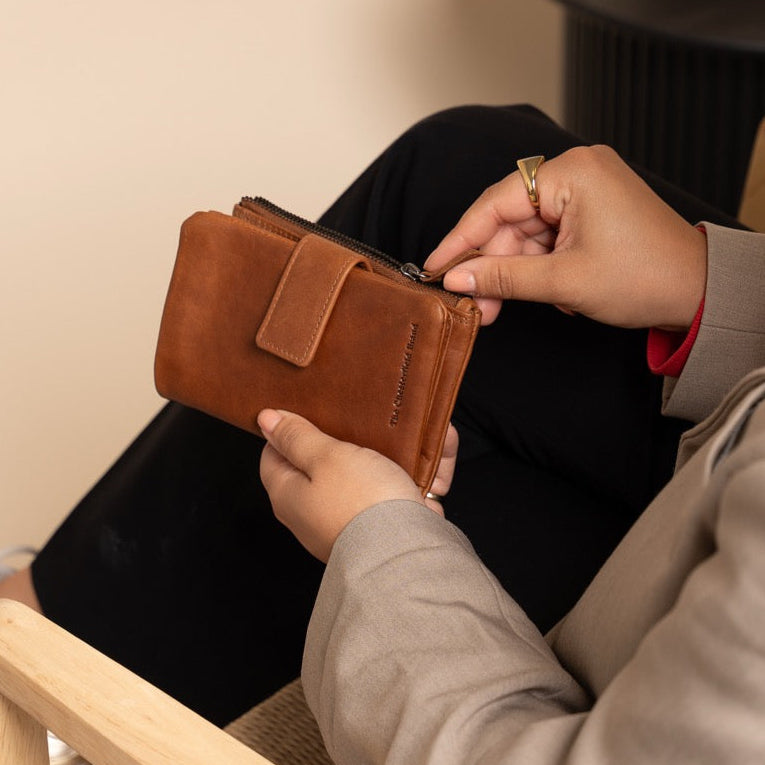 Person sitting on a chair holding a cognac wallet.