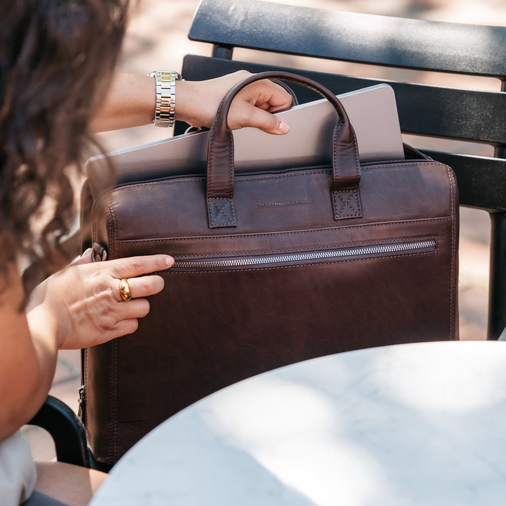 Person sitting on a bench with a brown leather briefcase