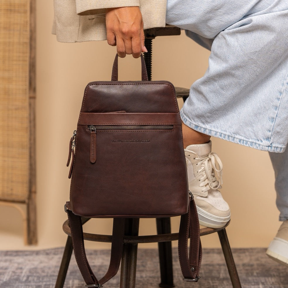Brown leather backpack Linford held by a woman sitting on a chair