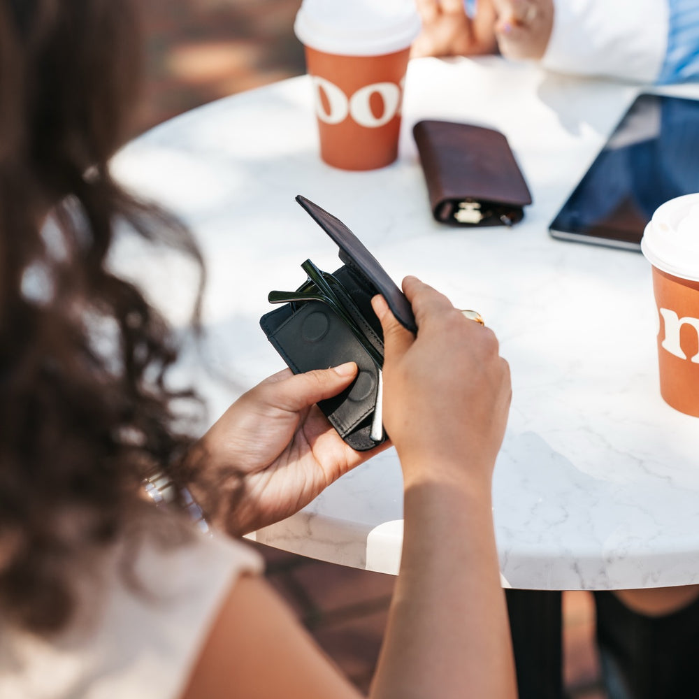 Person holding a black leather glasses case