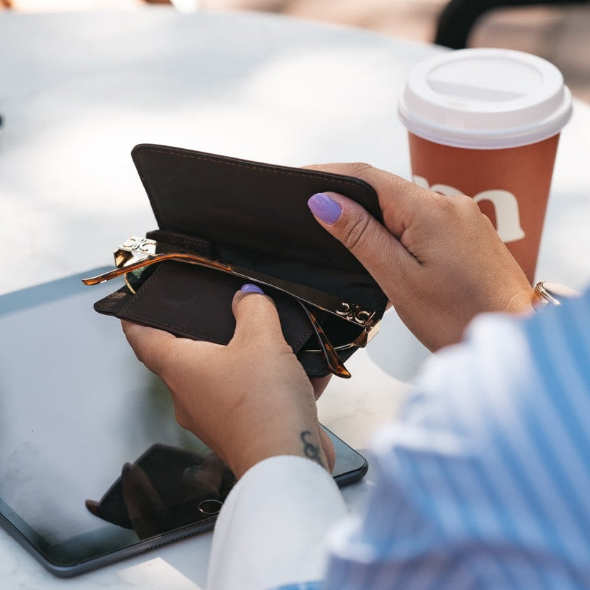 Person holding a brown leather glasses case