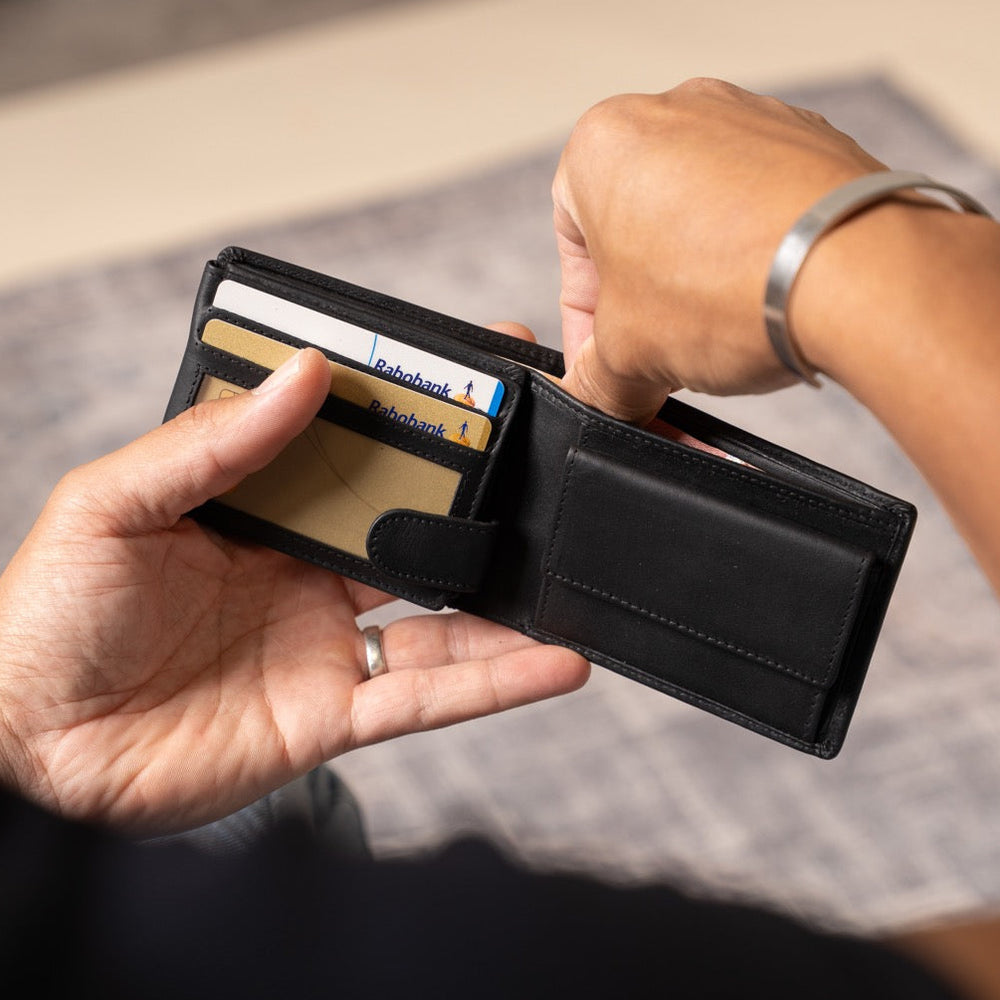 Person holding an open black wallet with cards inside, on a neutral background