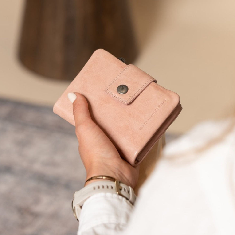 Person holding a pink wallet with a blurred background