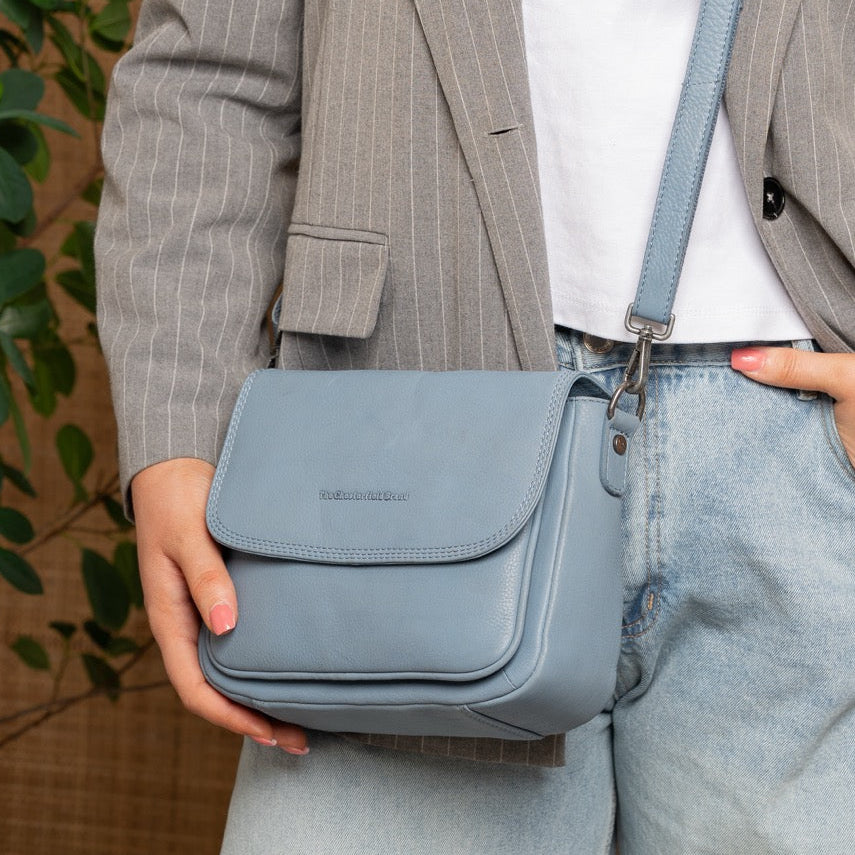 Person holding a blue handbag with a neutral background