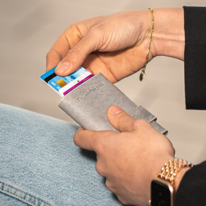 Person holding a wallet with a card on a neutral background