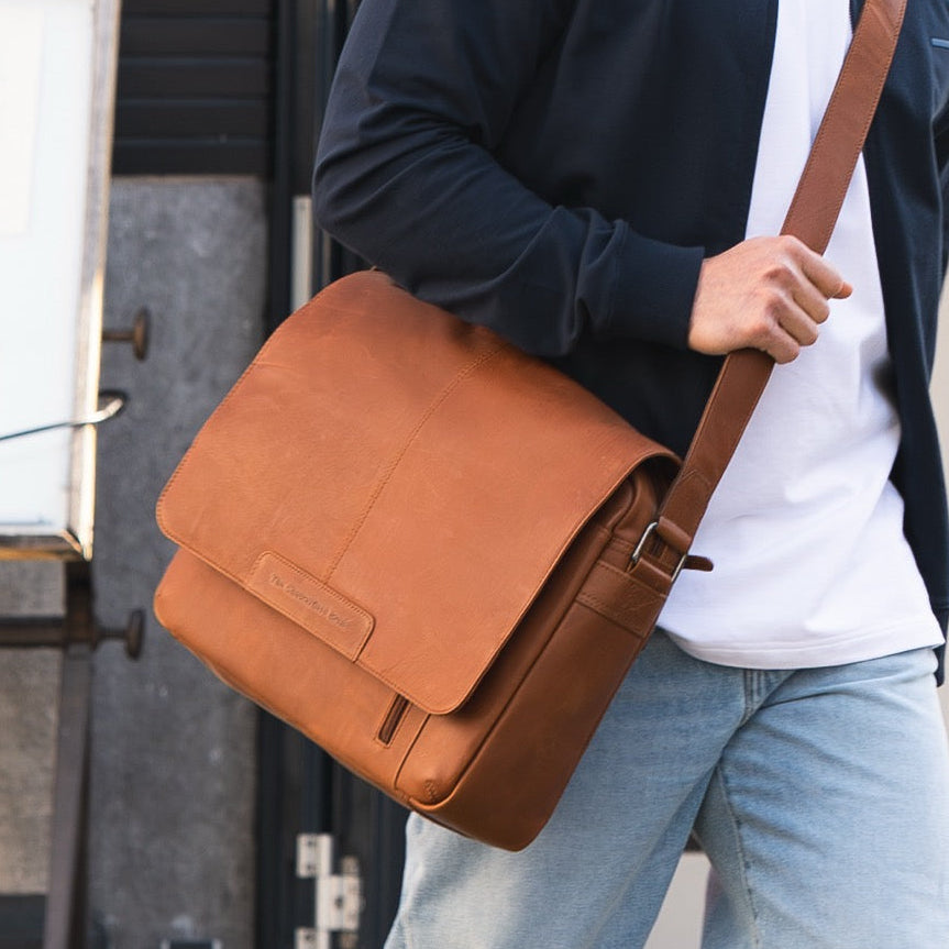 Person carrying a cognac leather bag in an urban setting