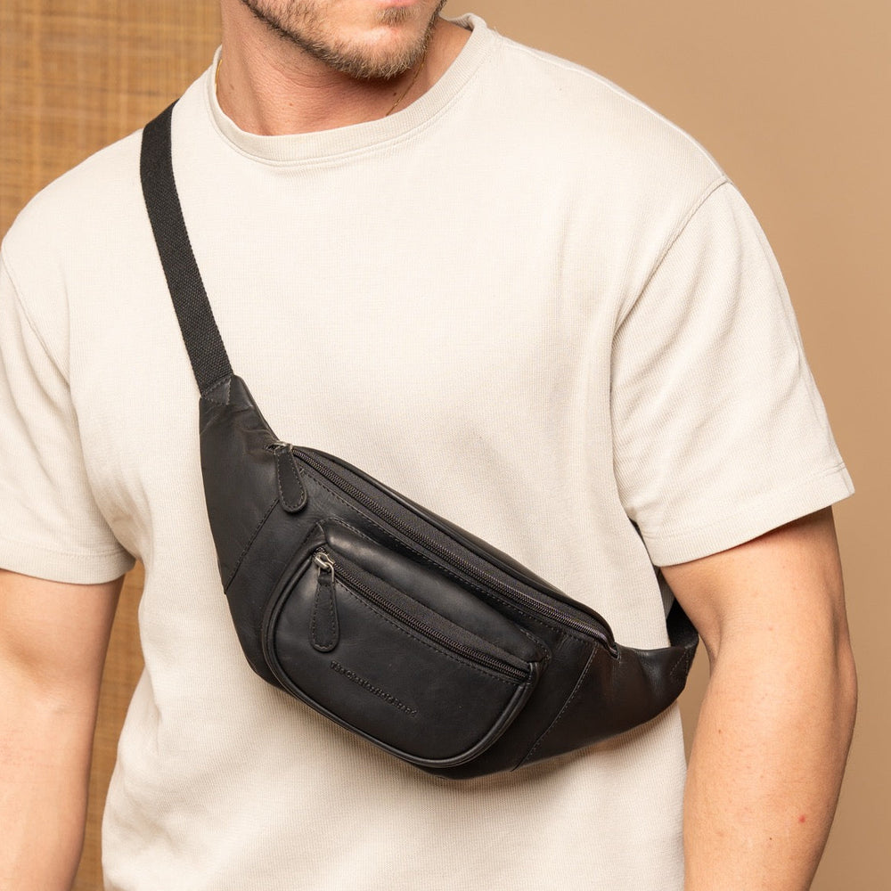 Man wearing a black leather waist bag against a beige background