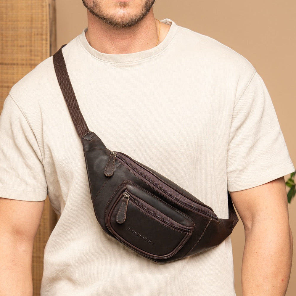 Man wearing a brown leather waist bag against a beige background