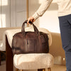 Person holding a brown leather bag in an indoor setting