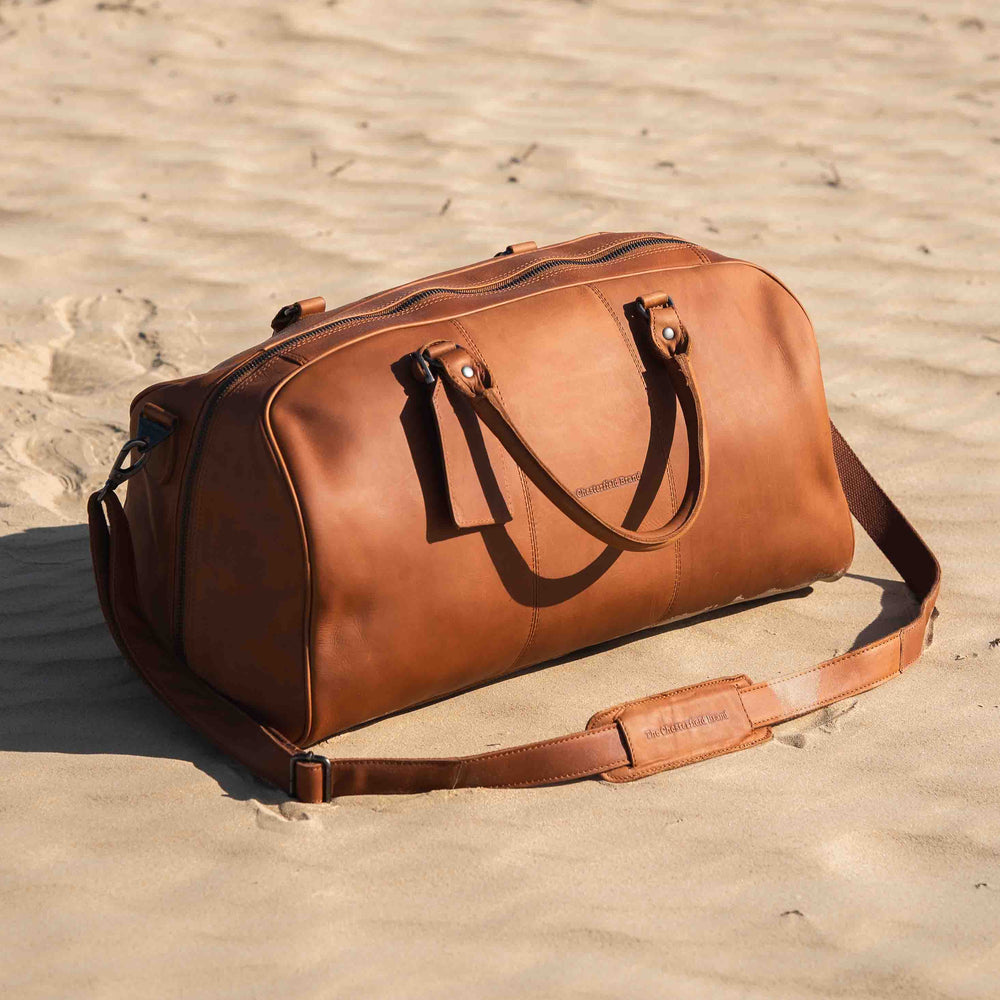 Cognac leather duffel bag on a sandy surface