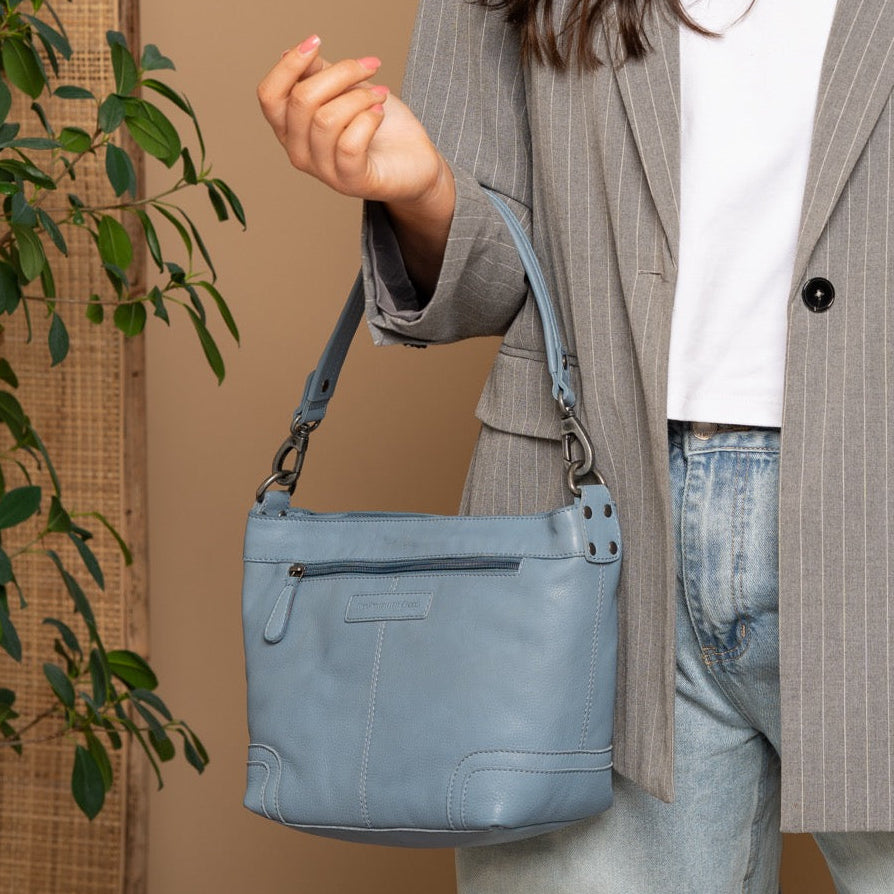 Person holding a blue handbag against a beige background