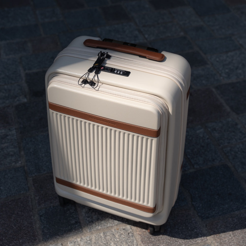 Beige suitcase with brown accents on a dark pavement