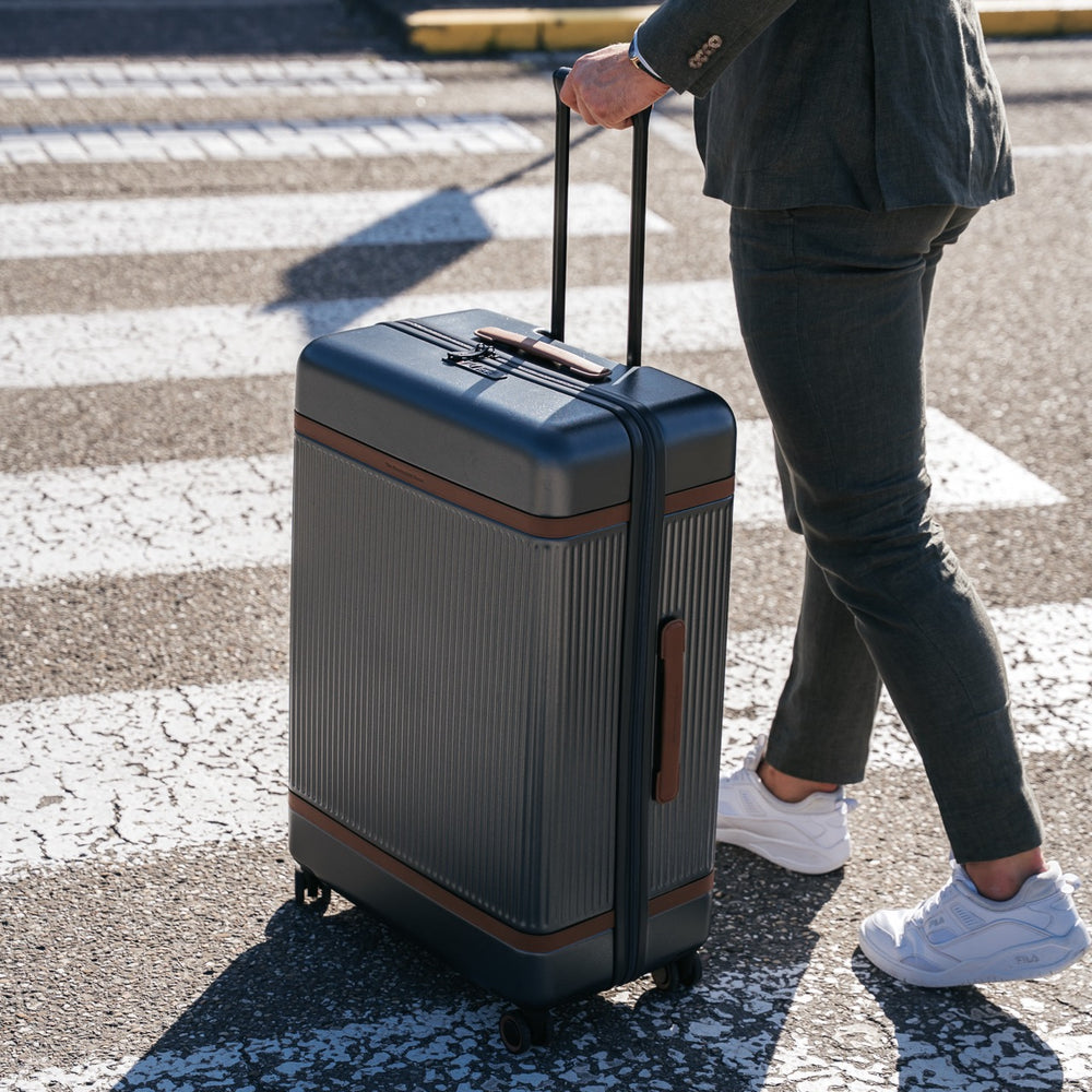 Person pulling a gray suitcase on a crosswalk