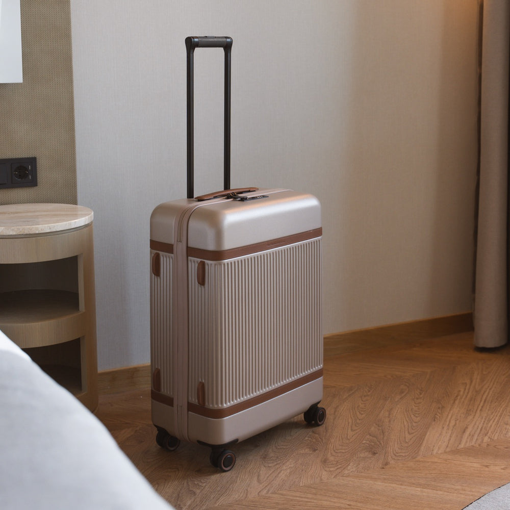 Beige suitcase with brown accents on a wooden floor in a room.